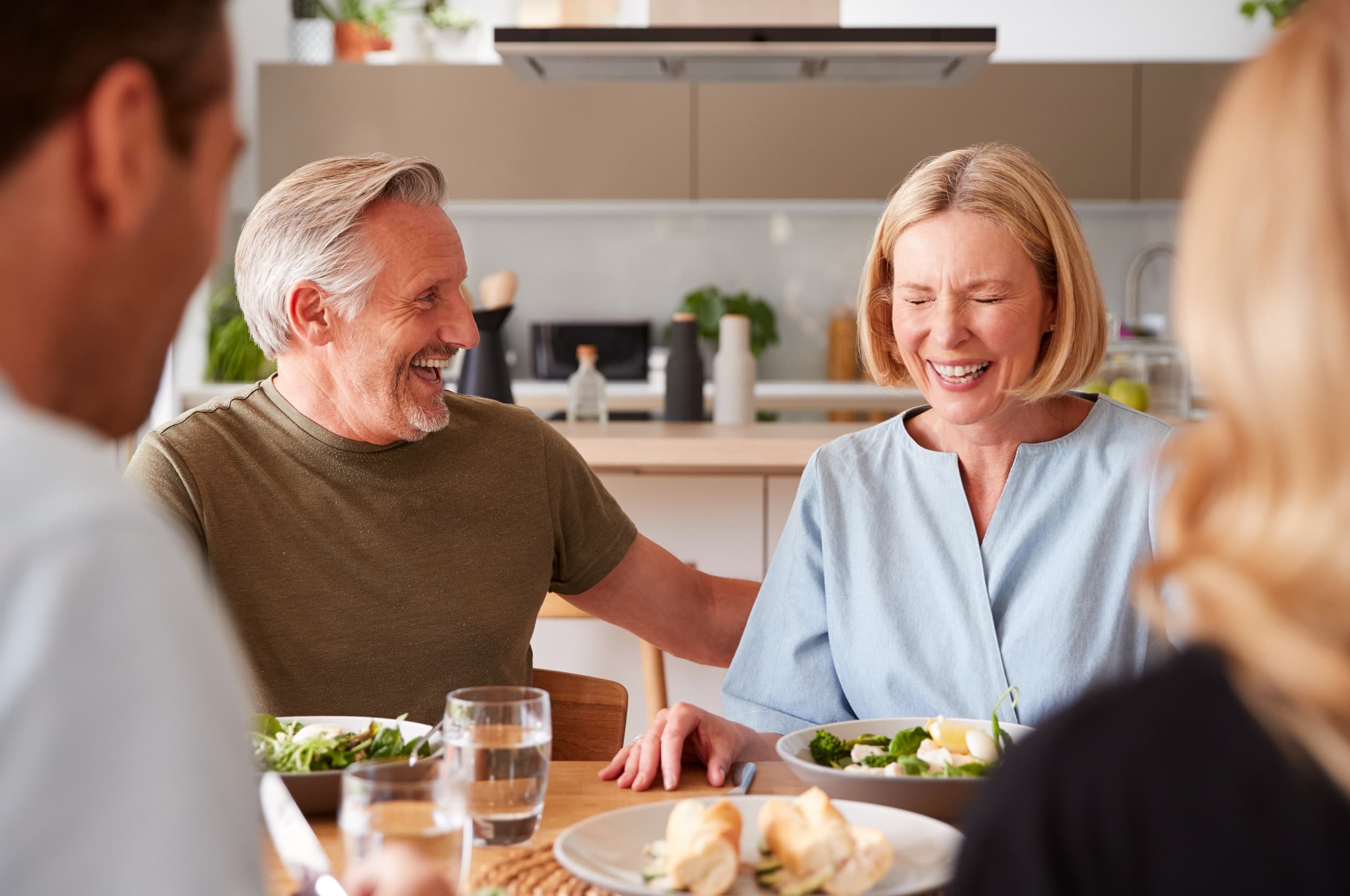 A family with senior parents and adult children smiling together over a meal